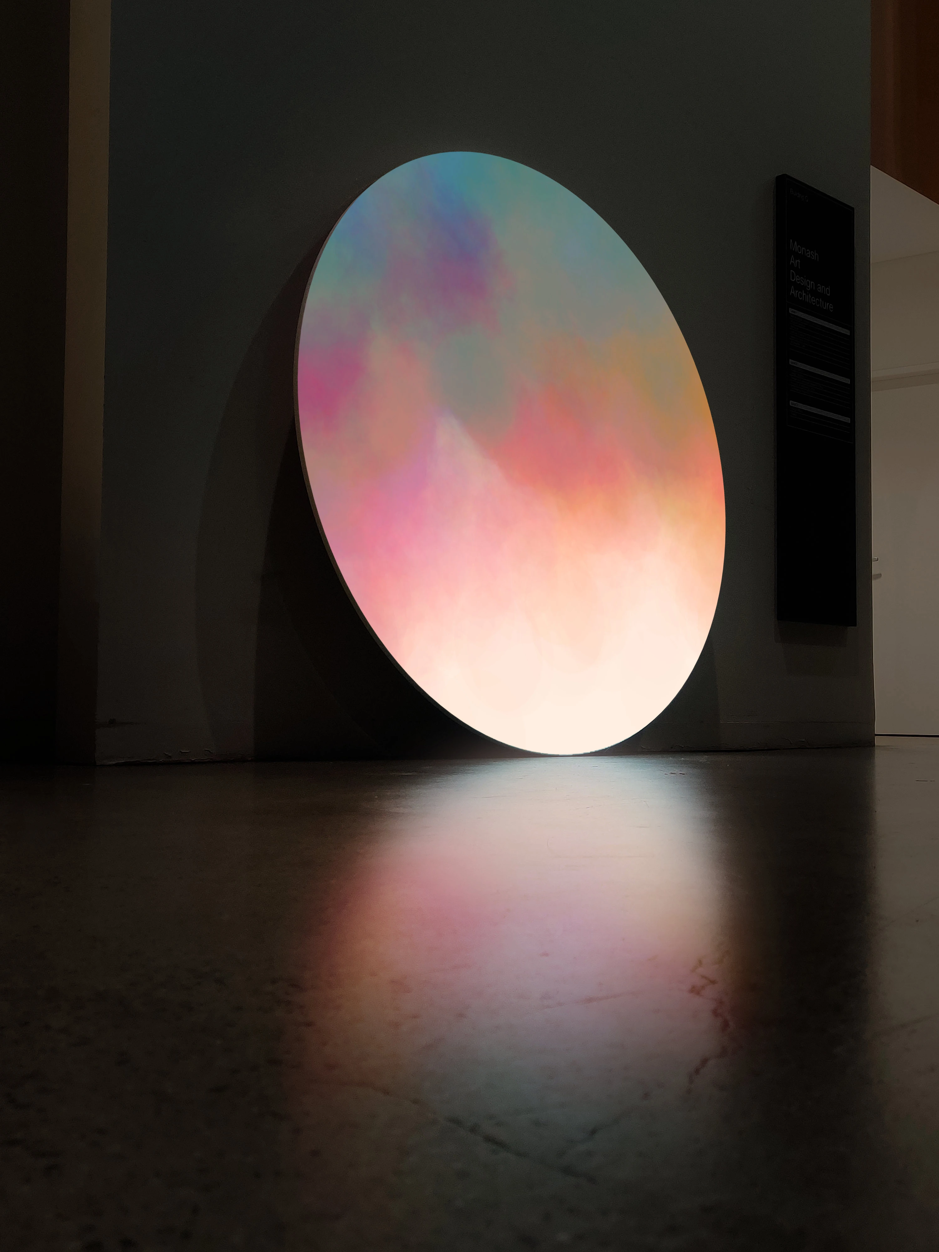 Side photo of the artwork, reflecting on the polished concrete like a full moon.